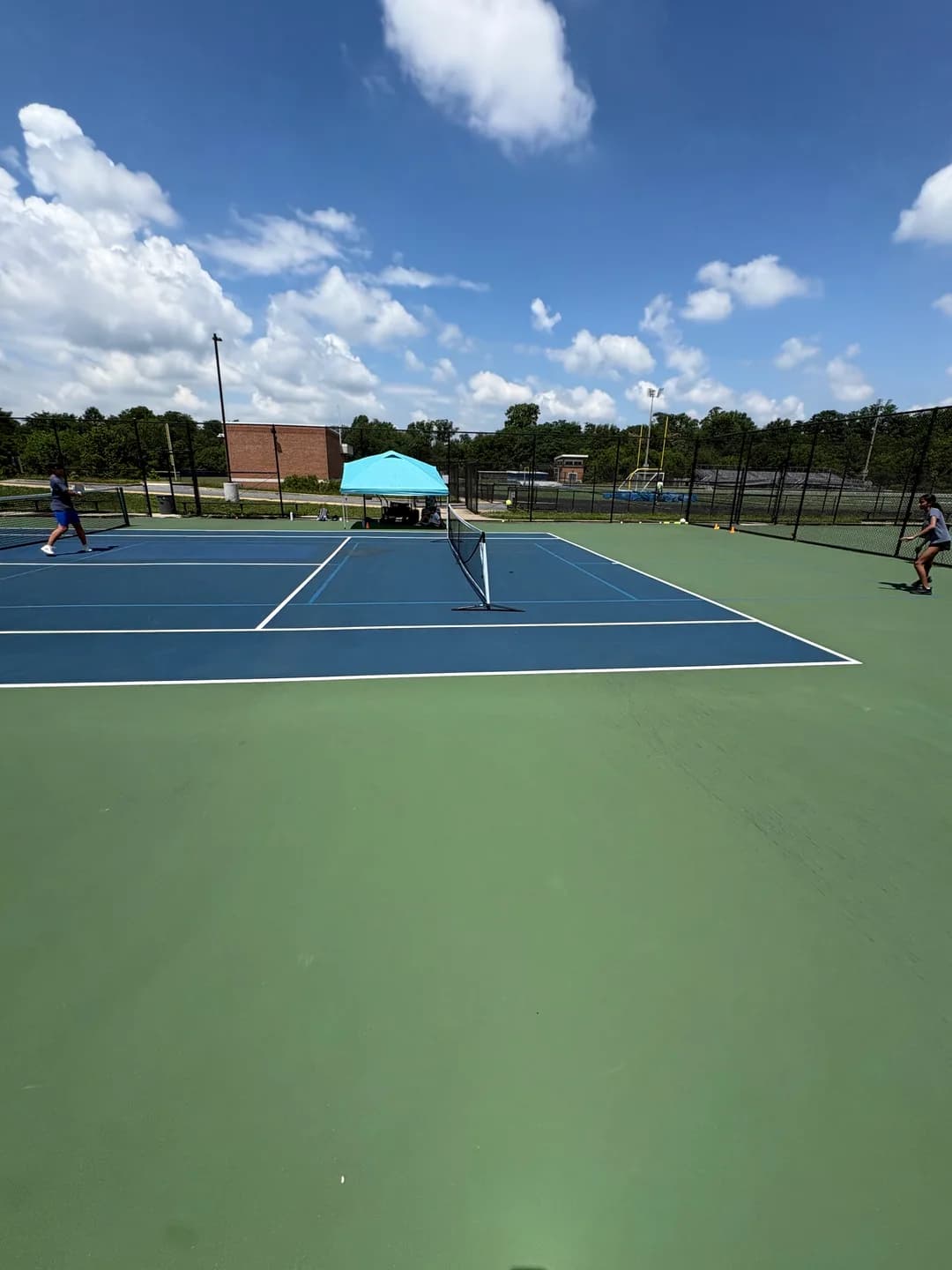 Young players rallying across blue and green outdoor pickleball courts