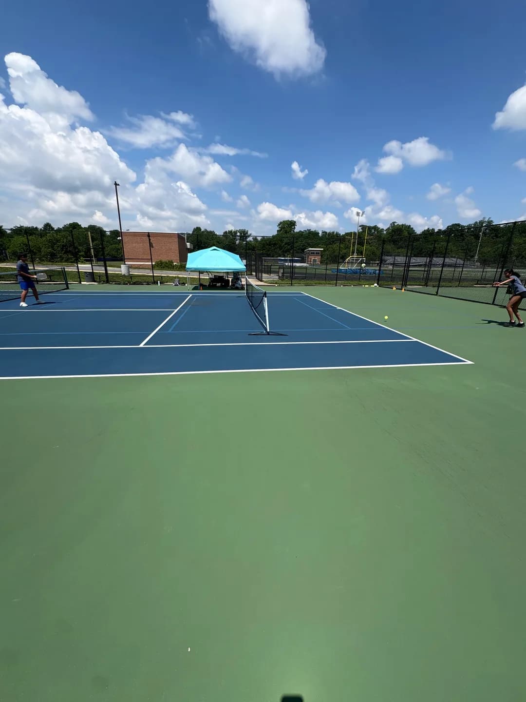 Young players rallying across blue and green outdoor pickleball courts