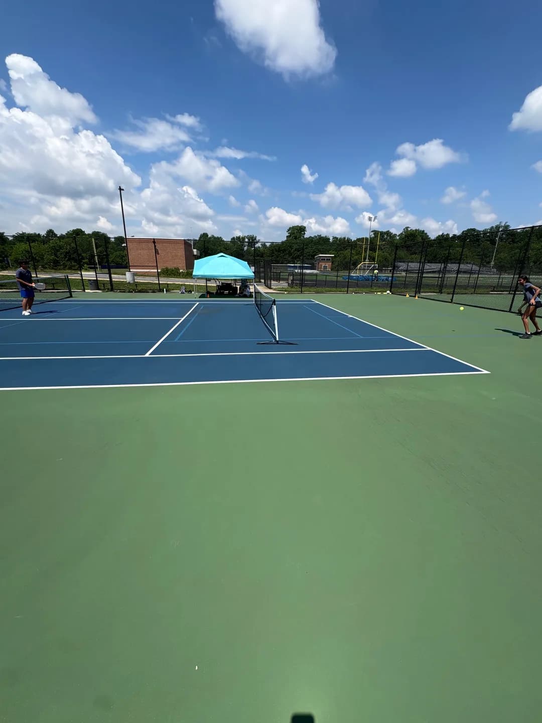 Young players rallying across blue and green outdoor pickleball courts