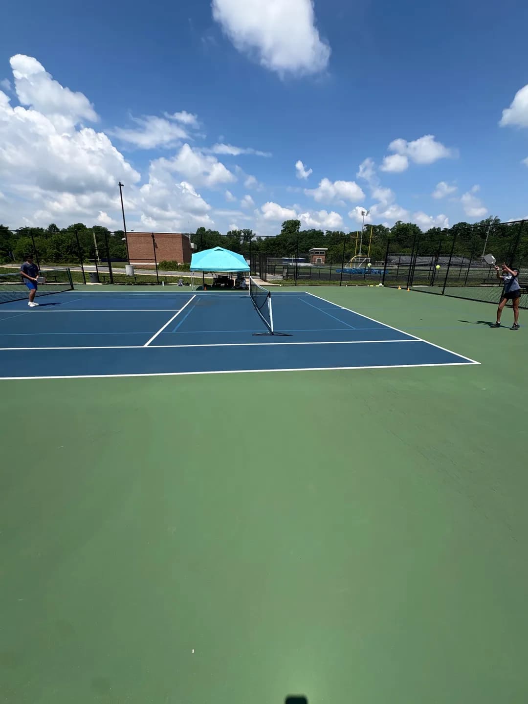 Young players rallying across blue and green outdoor pickleball courts
