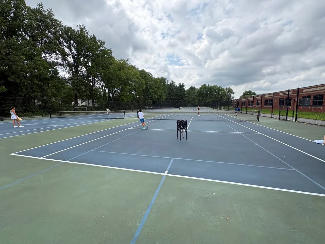 Young players rallying across blue and green outdoor pickleball courts