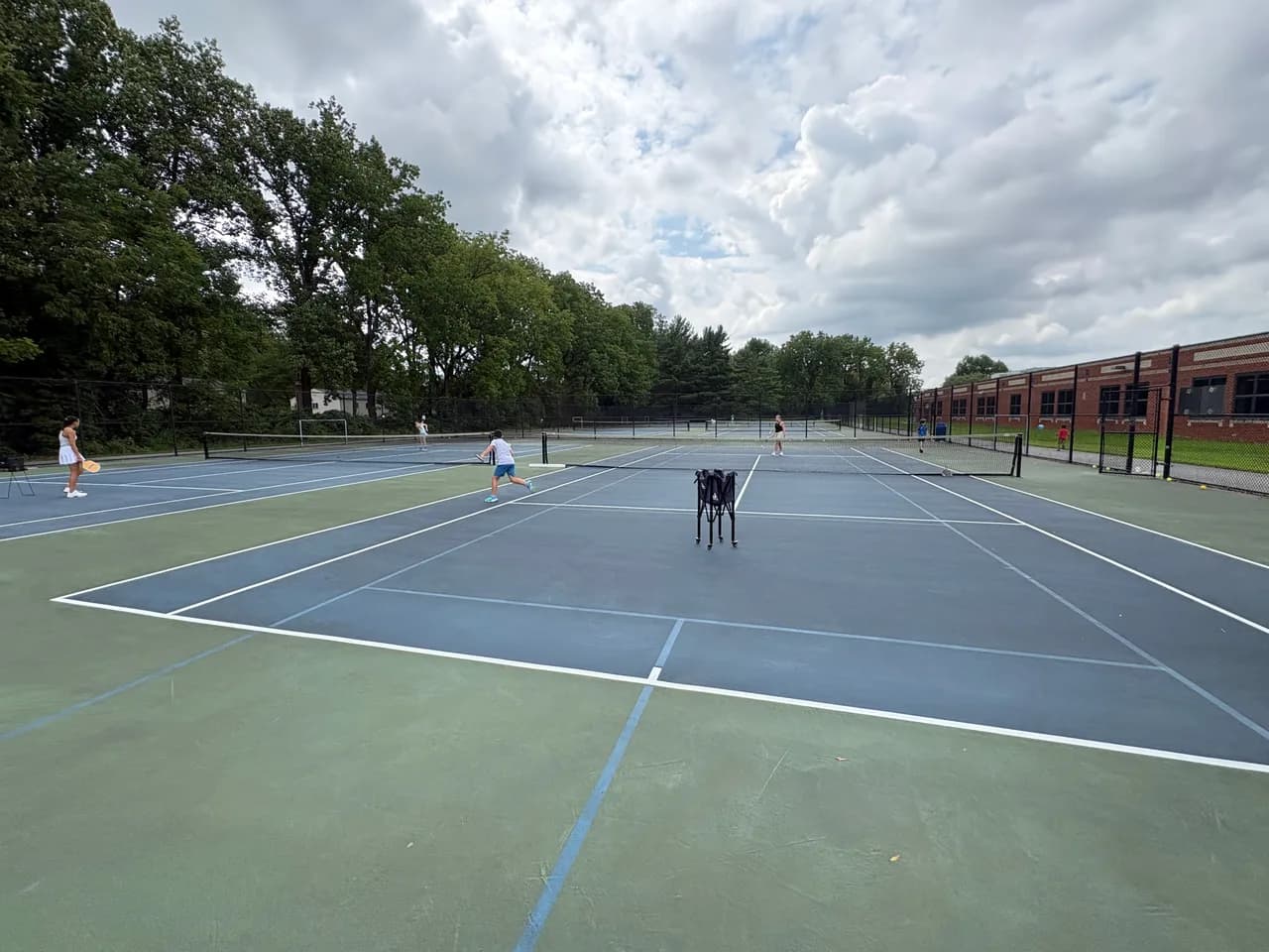 Young players rallying across blue and green outdoor pickleball courts