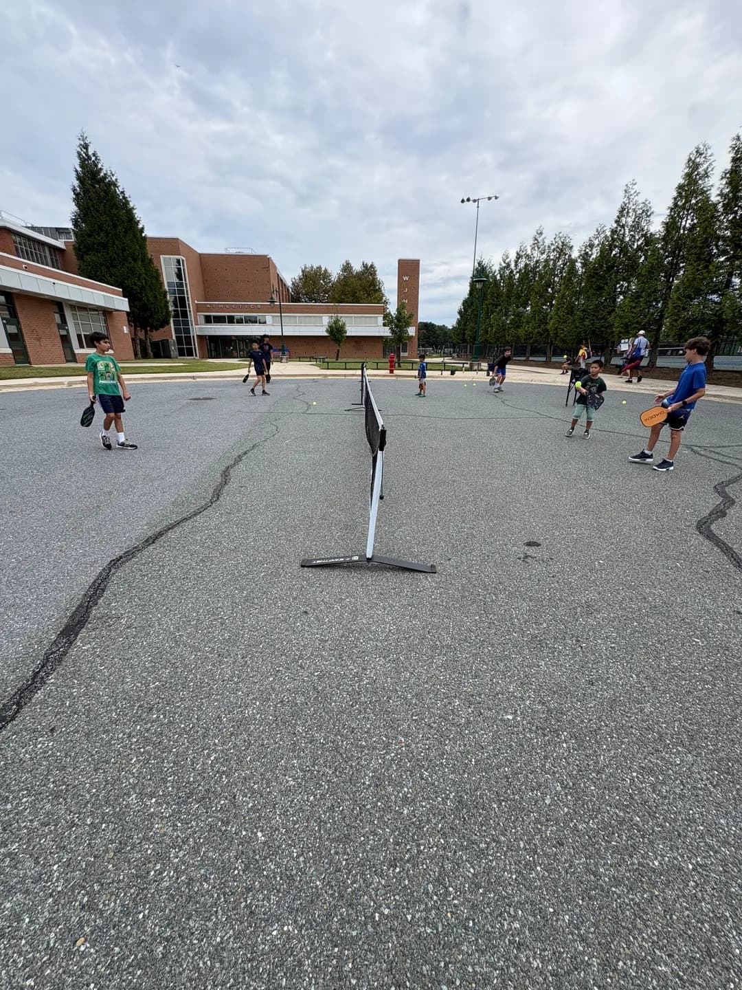 Young players rallying across portable pickleball nets outdoors
