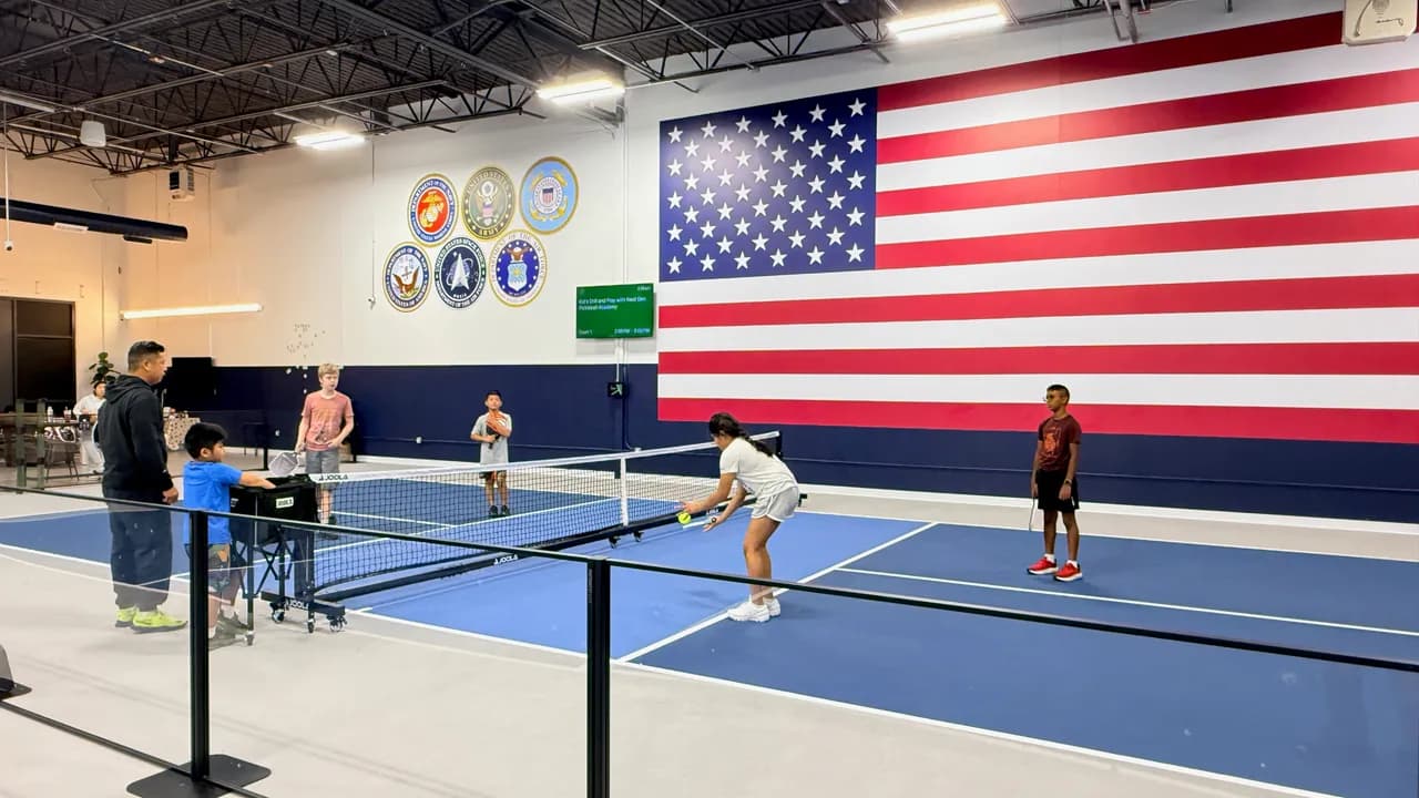 Young players practicing pickleball on indoor blue courts